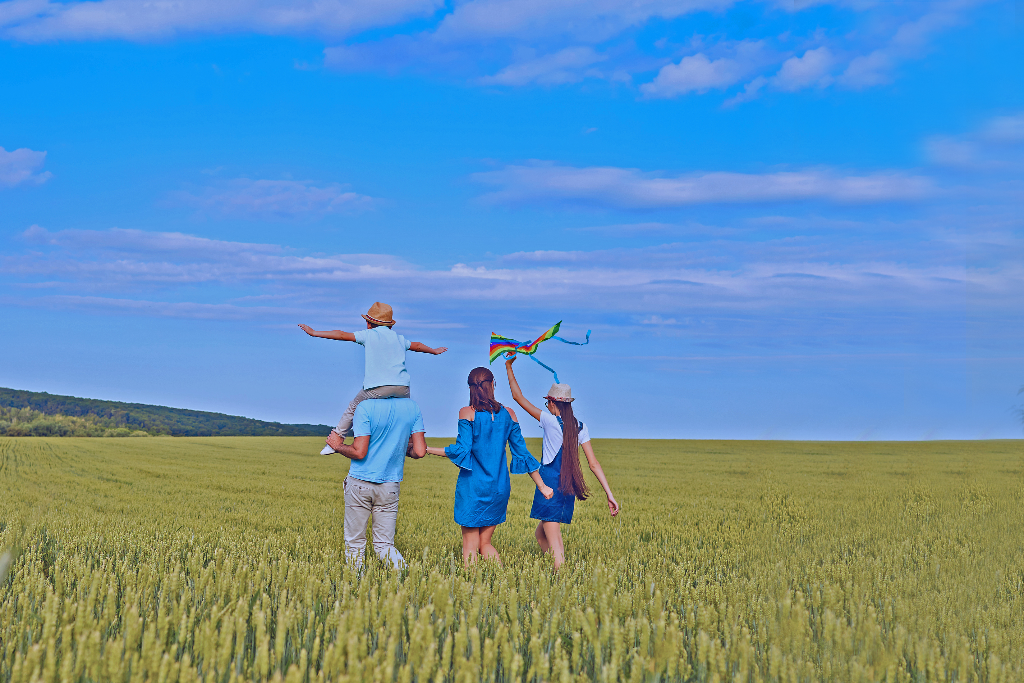 A happy family is walking in a wheat field in the summer
